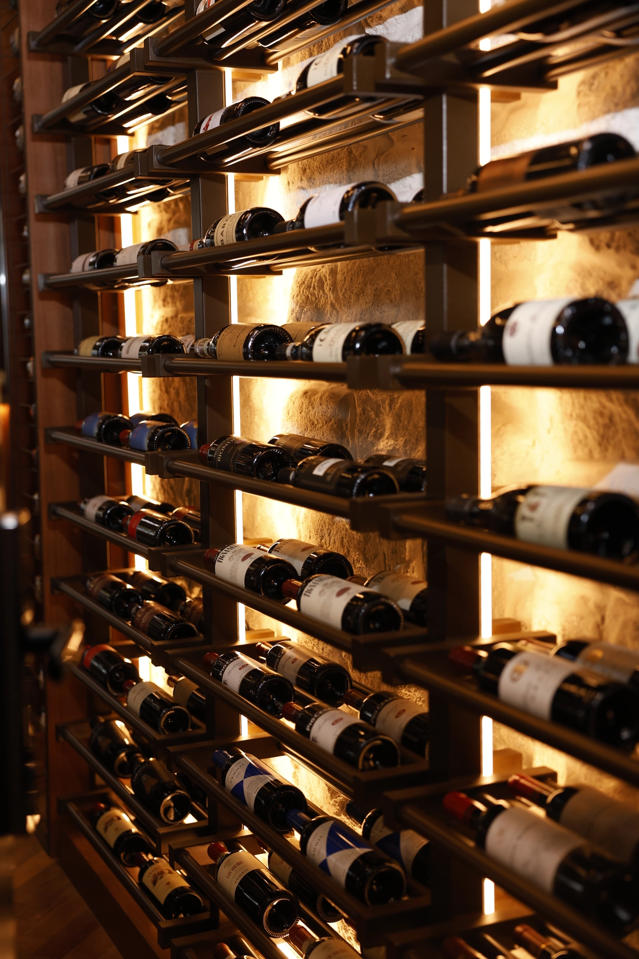 Climate-controlled wine cellar with bottles arranged on illuminated shelves.